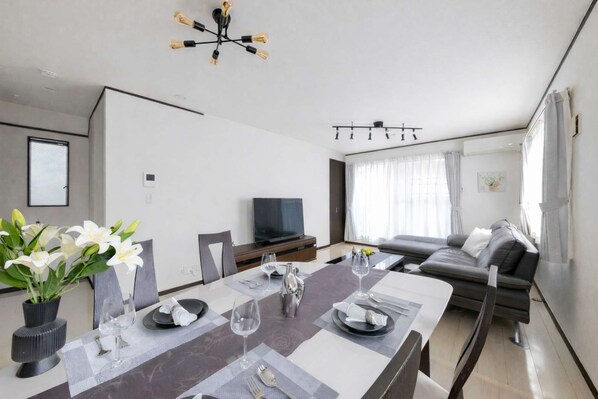 Una sala de estar moderna con comedor, televisor de pantalla plana y sofá.