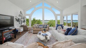 A spacious living room with a large TV, comfortable seating, a coffee table, and a view of the outdoors. - Meet Me In Paradise: CL Waterfront + Outdoor Fireplace + Pool Table + Ping Pong + 2 Living Areas (Canyon Lake)