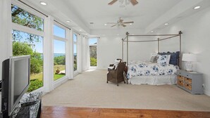 A bedroom with a four-poster bed, a television, and a view of the outdoors. - Meet Me In Paradise: CL Waterfront + Outdoor Fireplace + Pool Table + Ping Pong + 2 Living Areas (Canyon Lake)