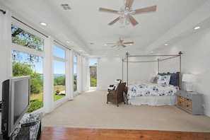 A bedroom with a four-poster bed, a television, and a view of the outdoors. - Meet Me In Paradise: CL Waterfront + Outdoor Fireplace + Pool Table + Ping Pong + 2 Living Areas (Canyon Lake)