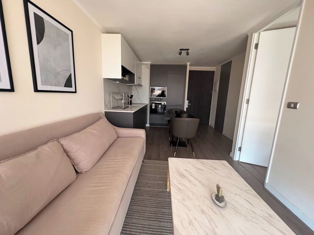 Un salon moderne avec un canapé, une table basse et une cuisine en arrière-plan.