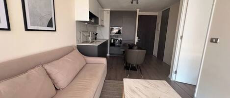 Una sala de estar moderna con un sofá, una mesa de centro y una cocina al fondo.
