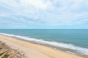 Ein Strand mit Zaun, Meer und blauem Himmel.
