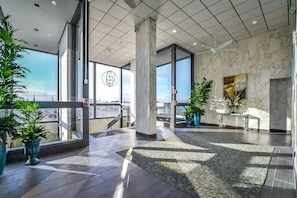 Eine geräumige Lobby mit großen Fenstern, Marmorwänden und Blumentöpfen.