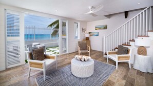 Ein geräumiges Wohnzimmer mit Balkon, weißen Möbeln, einem runden Couchtisch und einer Treppe.