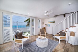 A spacious living room with a balcony, white furniture, a round coffee table, and a staircase. - Beachfront Villa with Plunge Pool - Sea Breeze Beach Villa (Fitts Village)