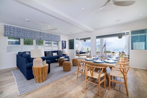 A modern living room with a sofa, coffee table, and dining area with chairs. - Beachfront Villa with Plunge Pool - Sea Breeze House (4 bed) (Fitts Village)