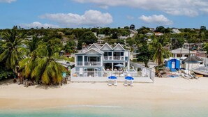 A beachfront property with a two-story house, a balcony, and a beach chair area. - Beachfront Villa with Plunge Pool - Sea Breeze House (4 bed) (Fitts Village)