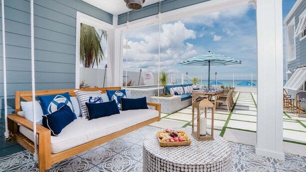 A balcony with a sofa, a table with a fruit basket, and a view of the sea. - Beachfront Villa with Plunge Pool - Sea Breeze House (4 bed) (Fitts Village)