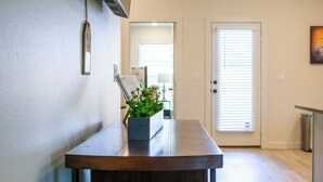 A hallway with a wooden bench, a potted plant, a door with blinds, and a small table with a lamp. - New 3-bedroom, 2 bath, 2 car garage, home in exceptional south Lubbock location. (Lubbock)