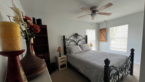 A bedroom with a bed, a nightstand, a lamp, a ceiling fan, a dresser, and a vase with flowers. -  Sublime Sunrise lakefront Dock, FirePit Kayak fishing Boat&boat trailer Parking (Hernando)