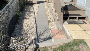 A pathway leading to a house with a gated entrance, surrounded by gravel and vegetation. -  Sublime Sunrise lakefront Dock, FirePit Kayak fishing Boat&boat trailer Parking (Hernando)