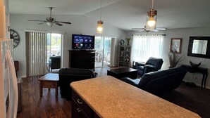 A spacious living area with a large kitchen island, ceiling fans, and a television. -  Sublime Sunrise lakefront Dock, FirePit Kayak fishing Boat&boat trailer Parking (Hernando)