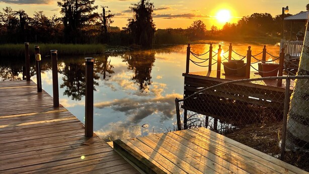 A wooden dock extending into a calm body of water with a sunset in the background. -  Sublime Sunrise lakefront Dock, FirePit Kayak fishing Boat&boat trailer Parking (Hernando)
