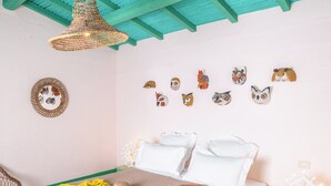 Quarto com cama, luminária pendente, obra de arte na parede e uma pequena mesa.