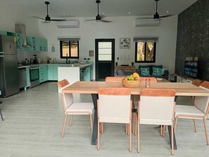 A modern kitchen with a dining area, including a wooden table and chairs, and a large window providing natural light. - Cozy house, between beach and Nature (Brasilito)
