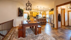 A spacious kitchen with wooden cabinets, a central island, and pendant lighting.