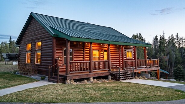 A log cabin with a porch, a staircase, and a metal roof.