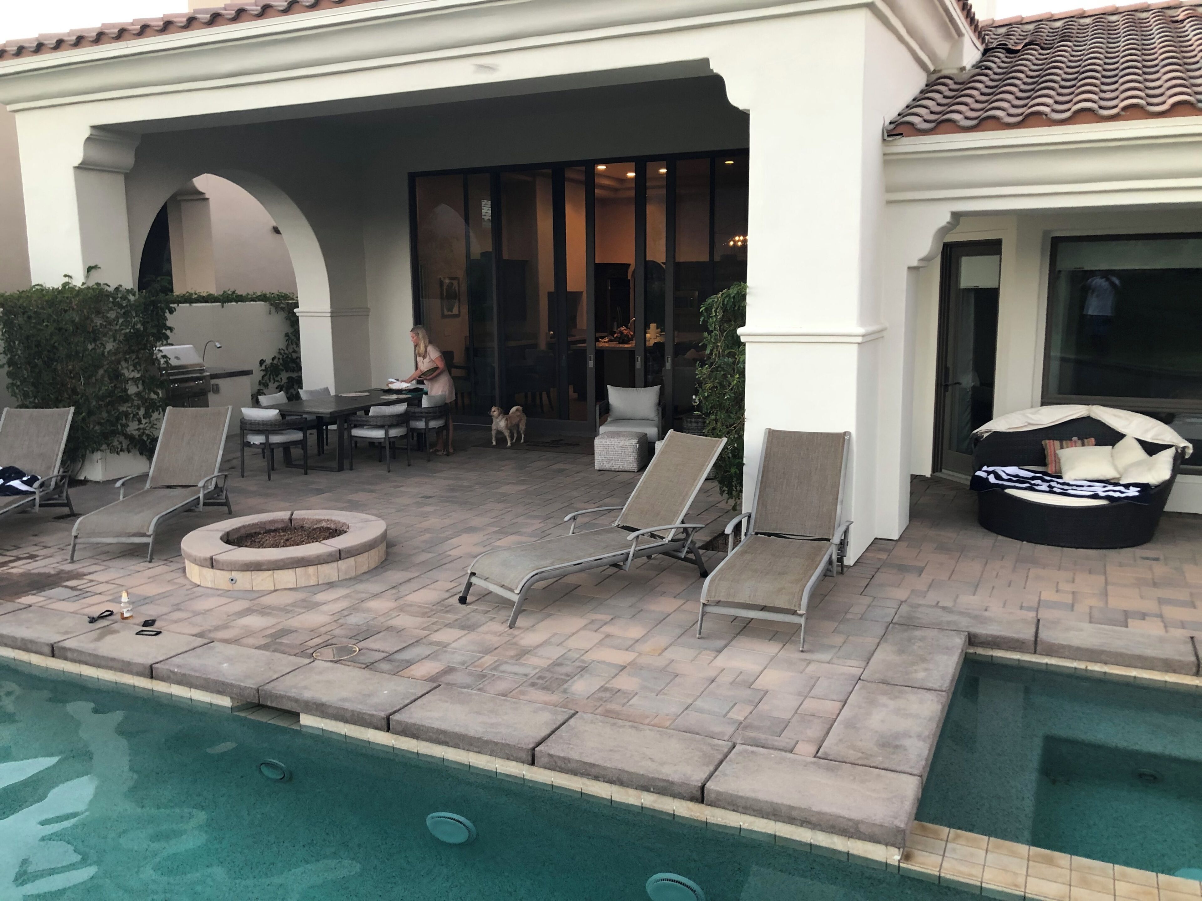 A poolside area with lounge chairs, a fire pit, and a covered seating area.