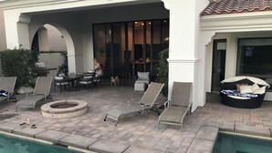 Un espace aménagé au bord de la piscine, avec des chaises longues, un foyer et un coin salon abrité.