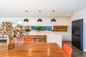 A modern kitchen with a central island, pendant lights, and a large aquarium. - Beachside Banksia - perfect beach stayvacation (East Ballina)