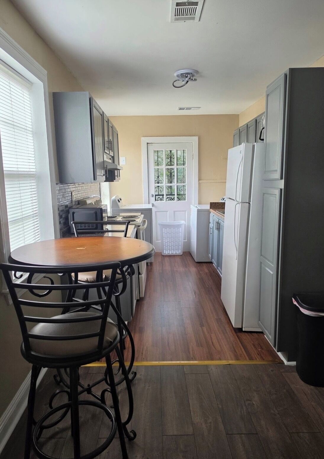 Una cocina con una mesa de comedor, sillas, un refrigerador y una ventana.