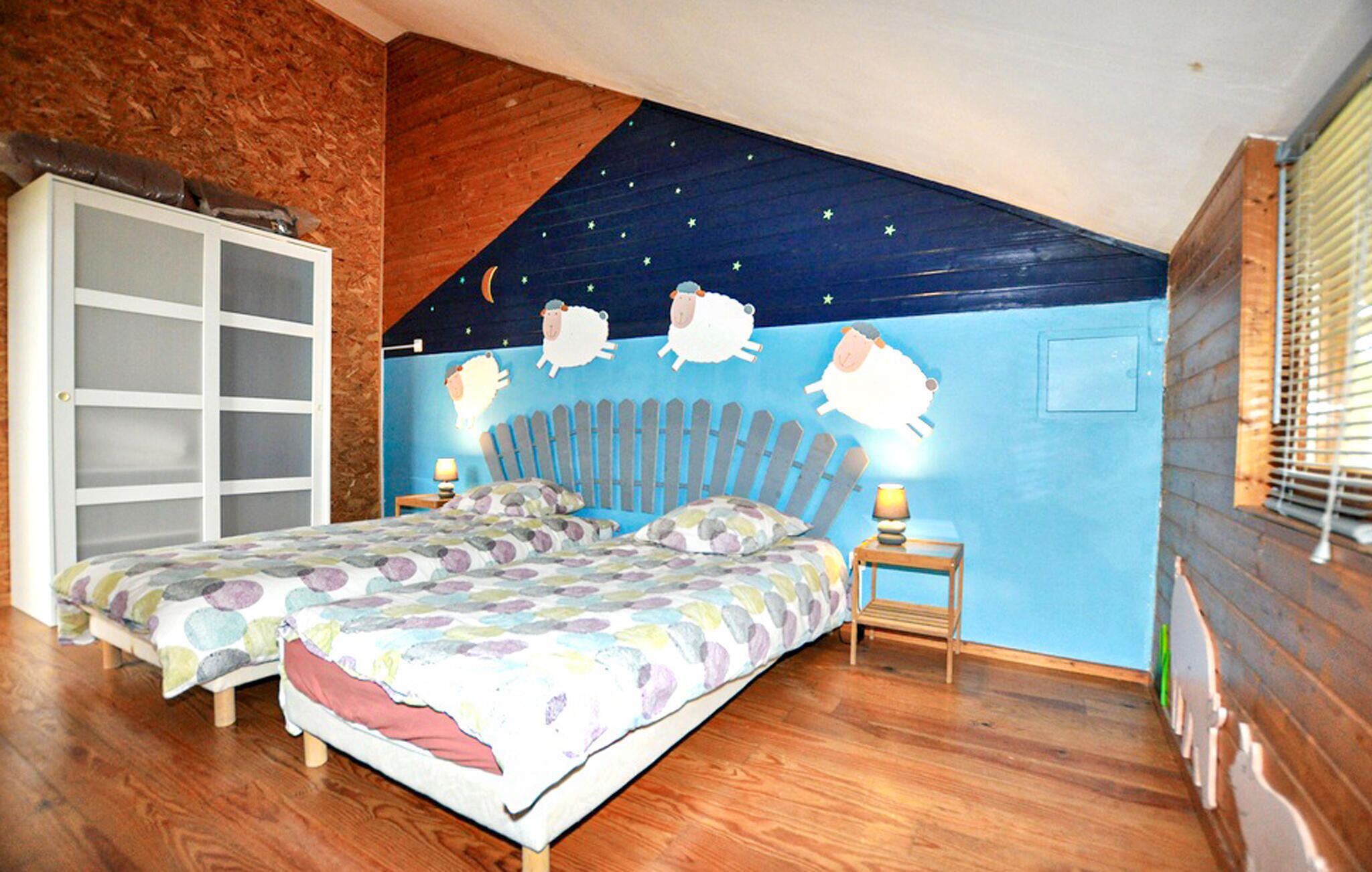 Un dormitorio con techo inclinado, dos camas, un mural del cielo nocturno y un armario de madera.