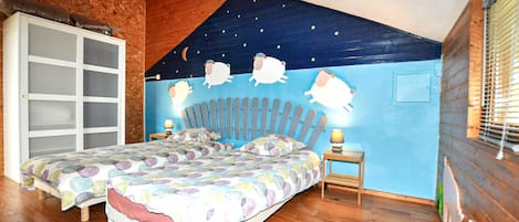 Un dormitorio con techo inclinado, dos camas, un mural del cielo nocturno y un armario de madera.