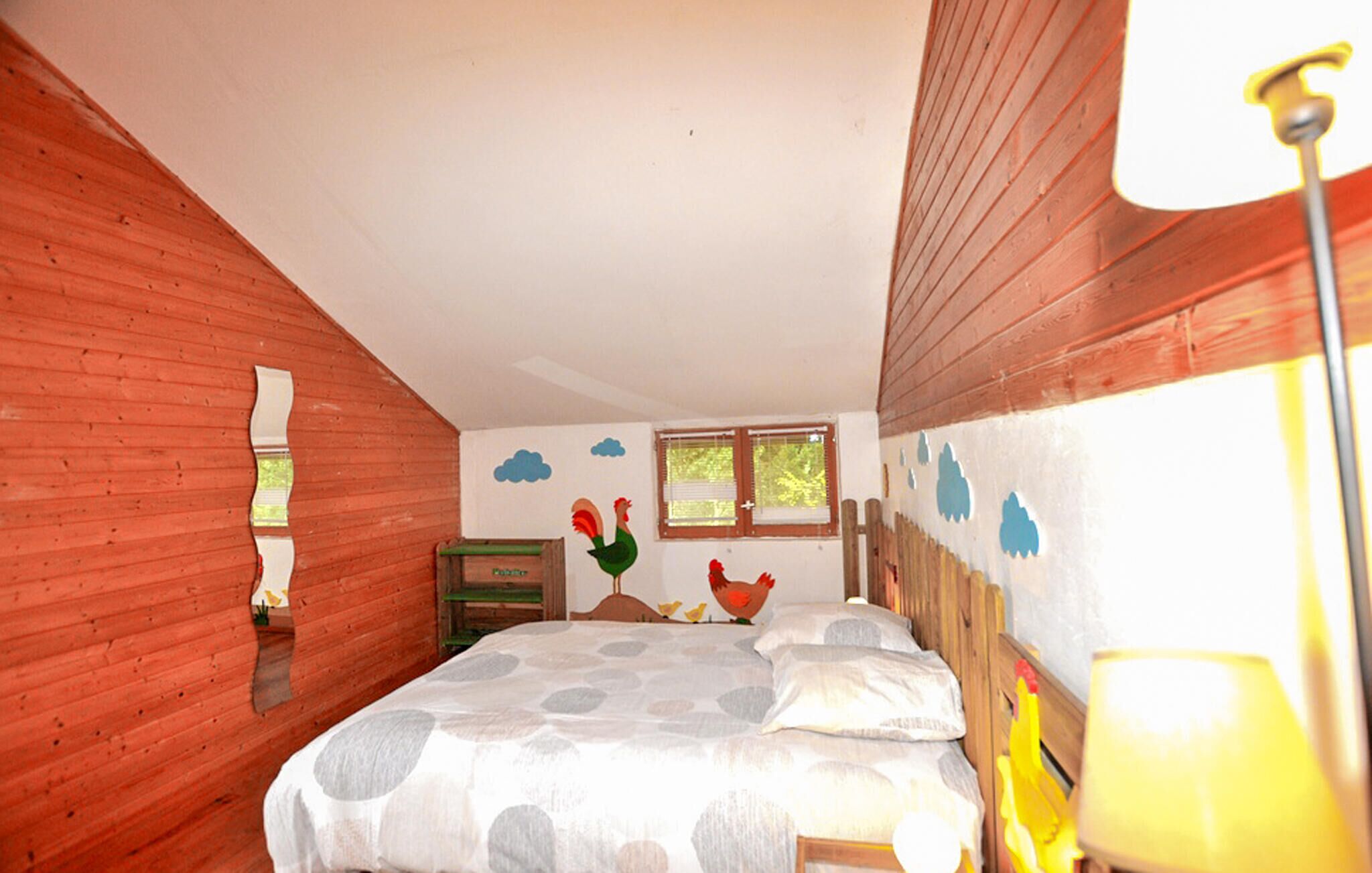 Une chambre à coucher avec un lit, des murs en bois, une fenêtre et une lampe.