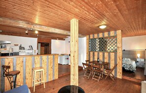 A rustic wooden interior with a kitchen area, a dining table with chairs, and a cozy seating area. - Authentique à la campagne (Cazalrenoux)