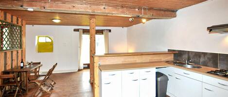 A kitchen with wooden cabinets, a dining area with a table and chairs, and a view of the outside.