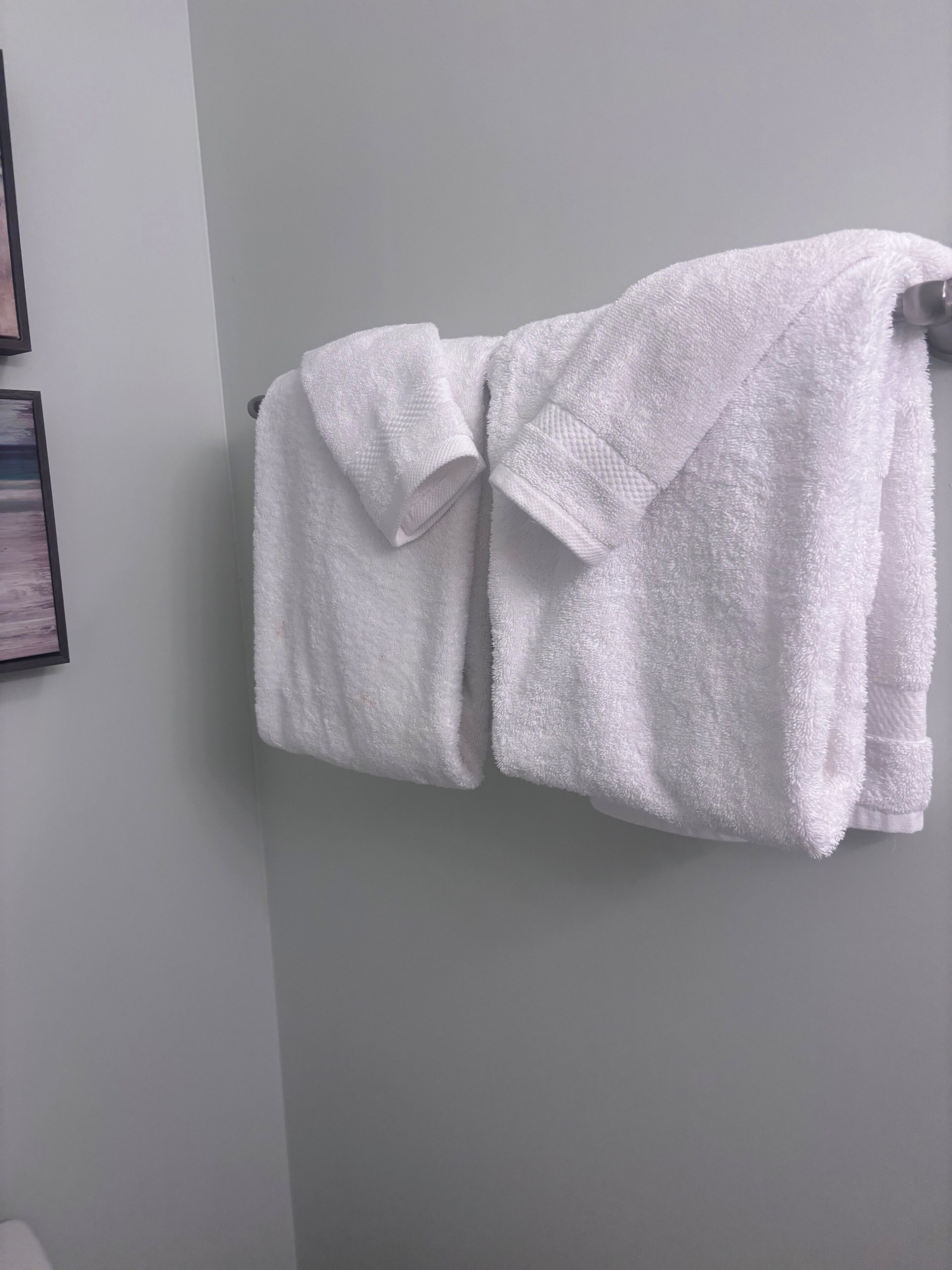 Ein weißes Handtuch, gefaltet und an einer Badezimmerwand aufgehängt.