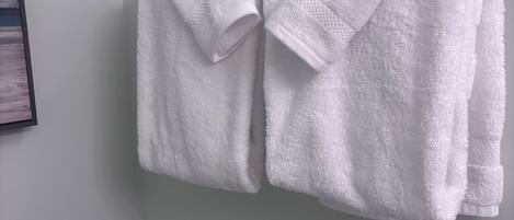 Ein weißes Handtuch, gefaltet und an einer Badezimmerwand aufgehängt.