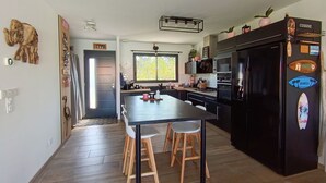 Une cuisine moderne avec un îlot central, des appareils électroménagers noirs et des tabourets en bois.