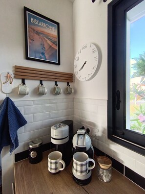 A kitchen with a coffee maker, two mugs, a clock, and a framed picture on the wall. - Family house with private heated pool, air conditioning, pool view (Biscarrosse)