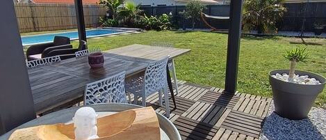 An outdoor patio with a table, chairs, a wooden sculpture, and a large planter.