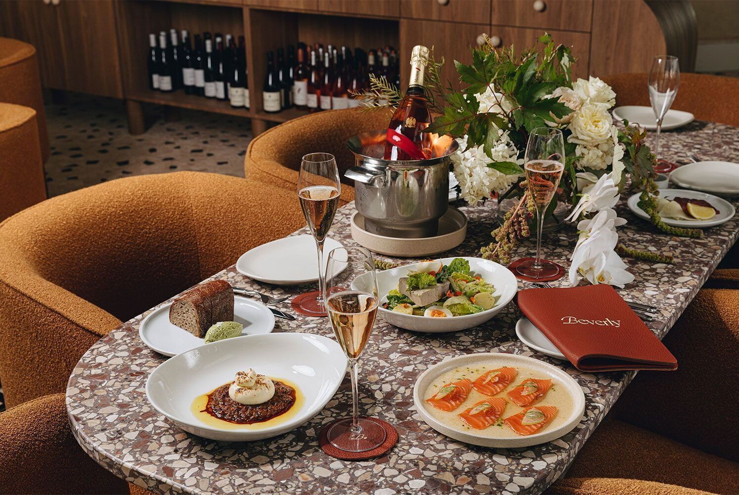 Una mesa de comedor con varios platos, vasos y una botella de champán.