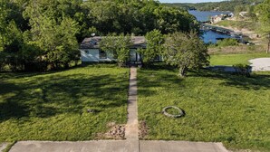 Une maison avec un jardin, un petit quai et un lac en arrière-plan.