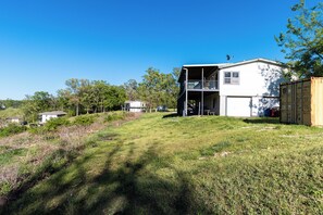 A two-story house with a balcony, surrounded by a grassy area and trees.