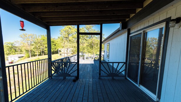 Une terrasse en bois avec des garde-corps, un espace abrité et une vue sur le paysage environnant.