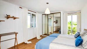 Une chambre à coucher avec un lit, un luminaire suspendu, une fenêtre avec des rideaux et un balcon offrant une vue.