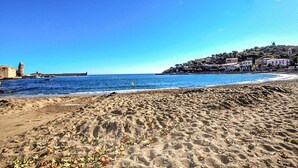 Une plage avec un phare, une côte rocheuse et des bâtiments situés sur une colline.