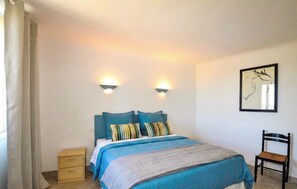 A bedroom with a bed, two bedside lamps, a chair, a nightstand, and a framed artwork on the wall. - Charmante villa piscine (Taulis)