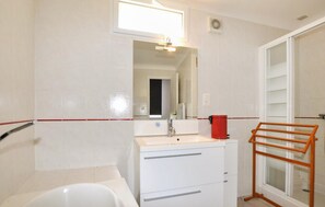 Ein Badezimmer mit Waschbecken, Spiegel und einem roten Eimer.