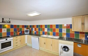 A kitchen with a microwave, oven, dishwasher, and washing machine. - Charmante villa piscine (Taulis)