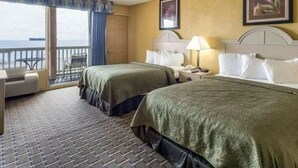 Habitación de hotel con dos camas, balcón y vista al mar.