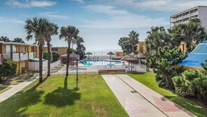 Zona de piscina con vista despejada, valla blanca y palmeras.