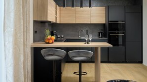 A modern kitchen with a wooden island, black bar stools, and built-in appliances. - Villa Maki (Istria - Svetvinčenat) (Svetvinčenat)