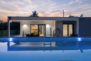 Una casa moderna amb piscina, zona de menjador i un dormitori.