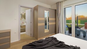 A bedroom with a bed, a wardrobe, a mirror, and a sliding glass door leading to an outdoor patio. - Villa Maki (Istria - Svetvinčenat) (Svetvinčenat)